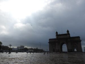 Gateway of India in Mumbai during monsoon season with cloudy skies and wet ground.