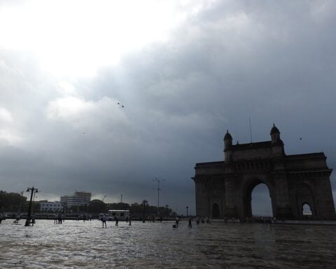 Gateway of India in Mumbai during monsoon season with cloudy skies and wet ground.