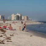 Families on Orange Beach, Alabama, with waves and condos along the Gulf Coast shoreline on a sunny day.
