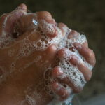 Person washing hands with soap and water, emphasizing hygiene.