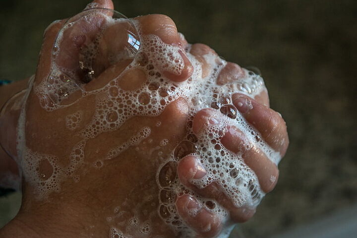 Person washing hands with soap and water, emphasizing hygiene.