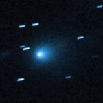 Hubble Space Telescope image of interstellar comet 3I/ATLAS showing a bright blue-white nucleus surrounded by a diffuse teardrop-shaped coma against a dark background with streaked stars appearing as short blue lines due to the telescope tracking the fast-moving comet.
