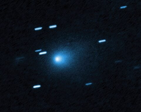 Hubble Space Telescope image of interstellar comet 3I/ATLAS showing a bright blue-white nucleus surrounded by a diffuse teardrop-shaped coma against a dark background with streaked stars appearing as short blue lines due to the telescope tracking the fast-moving comet.