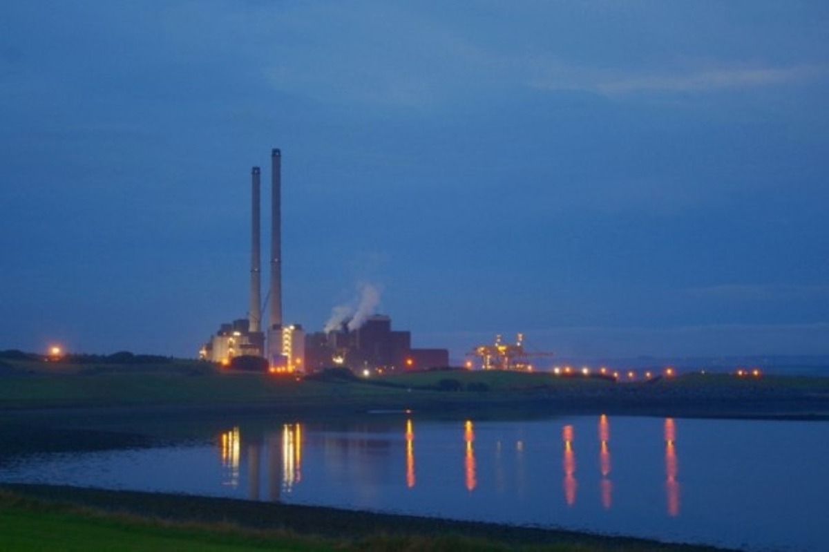 Evening view of ESB Moneypoint Power Station on the Shannon Estuary, twin stacks lit against a deep blue sky with lights reflecting on calm water, County Clare.