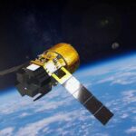 Artist rendering of JAXA HTV-X cargo spacecraft orbiting Earth with solar panels extended and cargo module visible against blue planet background