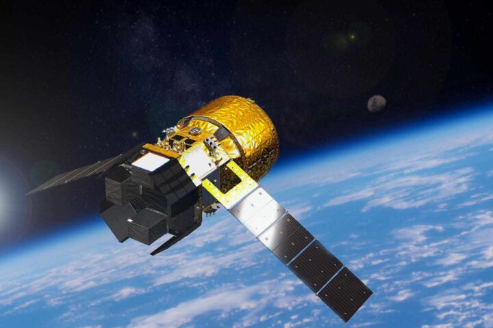 Artist rendering of JAXA HTV-X cargo spacecraft orbiting Earth with solar panels extended and cargo module visible against blue planet background
