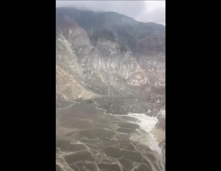 Aerial view of debris from a landslide in Southeast Alaska, showing dirt, rock, and debris filling an area of the fjord near South Sawyer Glacier.