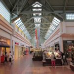 Interior of Greendale Mall in Worcester, Massachusetts, showing retail stores and shoppers walking along a wide indoor corridor.