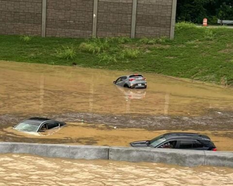 Flooded interstate with stalled vehicles and emergency lights visible in the distance. Photo Source: @JCGroves (X formerly Twitter)