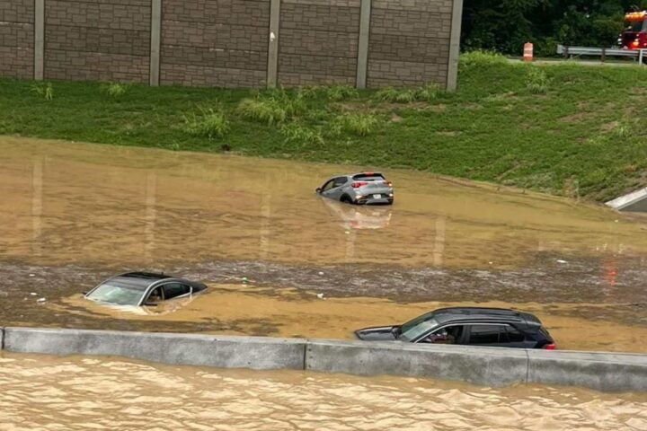 Flooded interstate with stalled vehicles and emergency lights visible in the distance. Photo Source: @JCGroves (X formerly Twitter)