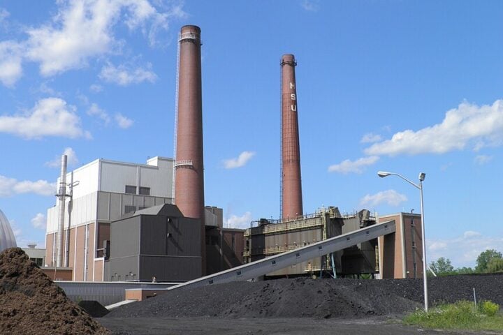 T.B. Simon Power Plant with tall brick smokestack and industrial buildings at Michigan State University campus in East Lansing, Michigan.