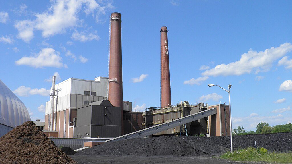 T.B. Simon Power Plant with tall brick smokestack and industrial buildings at Michigan State University campus in East Lansing, Michigan.