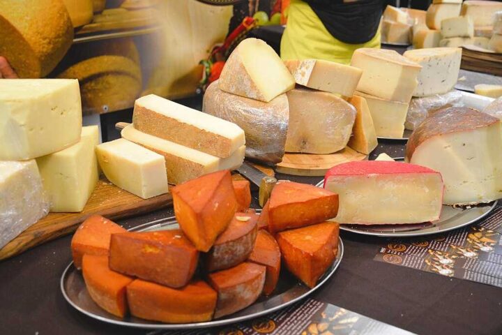 Representative Image. Assortment of various cheese types including soft cheese and orange-colored cheese displayed on a round metal serving platter.
