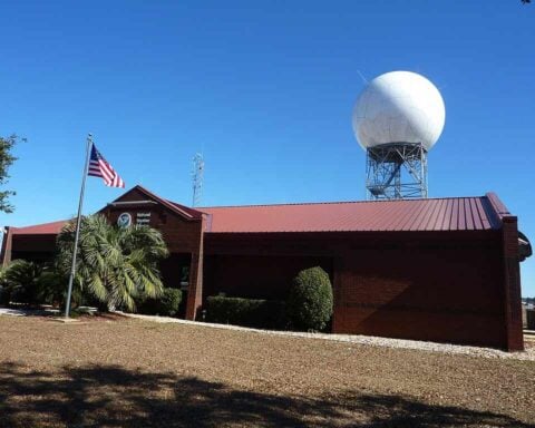 National Weather Service forecast office building with a NEXRAD Doppler radar dome at Mobile Regional Airport in Mobile, Alabama, under a clear blue sky.