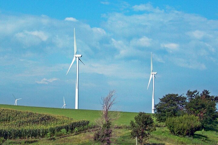 Wind turbines at Adair Wind Farm in Iowa, seen from open fields under a clear blue sky near Interstate 80.