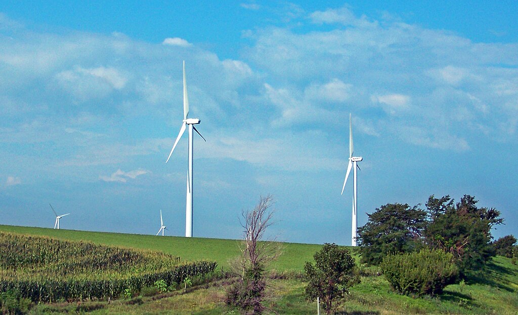 Wind turbines at Adair Wind Farm in Iowa, seen from open fields under a clear blue sky near Interstate 80.