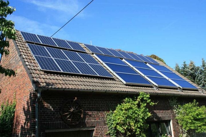 Barn roof in Western Europe with multiple solar panels installed, part of a combined heat and power system generating electricity and heat.