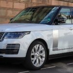 Front-left view of a white Range Rover Autobiography SDV8 parked near a brick wall.