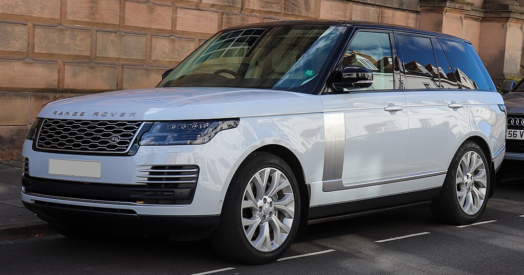 Front-left view of a white Range Rover Autobiography SDV8 parked near a brick wall.