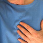 Person wearing a blue shirt with a hand on the chest, suggesting possible chest discomfort