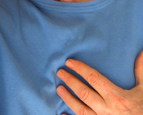 Person wearing a blue shirt with a hand on the chest, suggesting possible chest discomfort