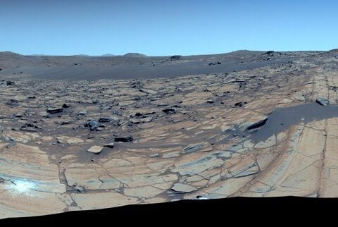 Enhanced-color 360° mosaic at ‘Falbreen’ showing fractured olivine-rich bedrock, distant hills, and a deceptively blue Martian sky.