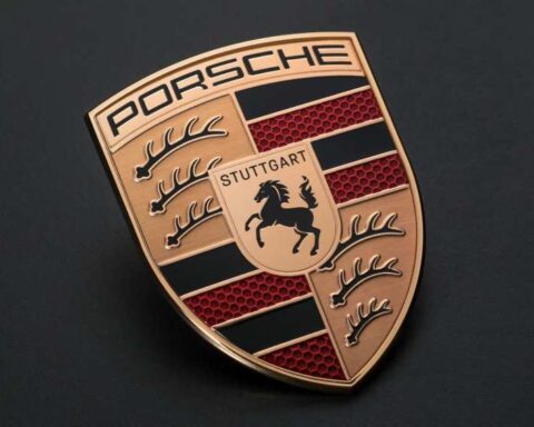 Porsche logo emblem with metallic gold finish on dark background representing the brand’s identity