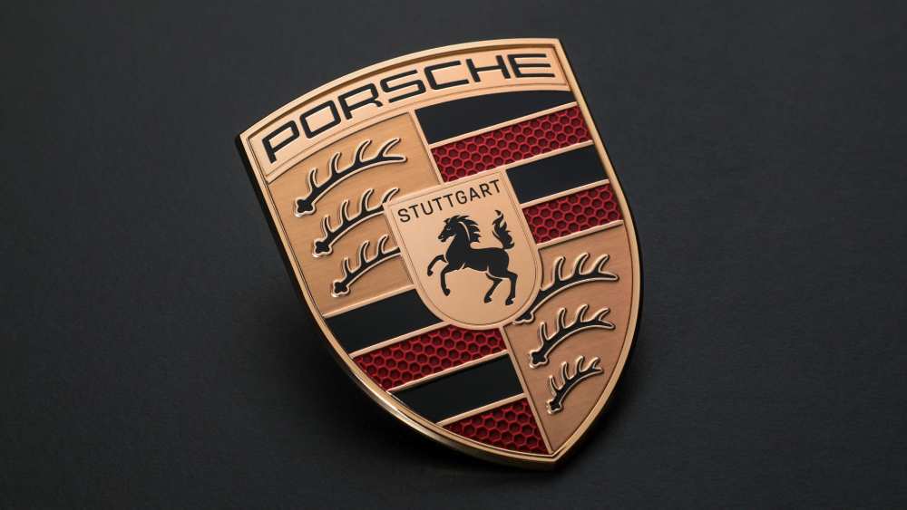 Porsche logo emblem with metallic gold finish on dark background representing the brand’s identity