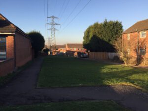 Residential street in Willenhall, Coventry, with large electricity pylons and power lines crossing the skyline, highlighting the intersection of urban life and the UK’s power infrastructure.