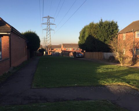 Residential street in Willenhall, Coventry, with large electricity pylons and power lines crossing the skyline, highlighting the intersection of urban life and the UK’s power infrastructure.
