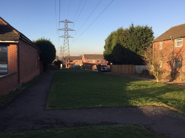 Residential street in Willenhall, Coventry, with large electricity pylons and power lines crossing the skyline, highlighting the intersection of urban life and the UK’s power infrastructure.