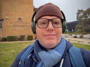 Richard Boyle wearing a beanie, glasses, and headphones, standing outside the Federal Court of Australia in Canberra.