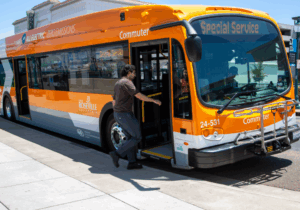 Orange all-electric Roseville Commuter bus with ‘Special Service’ on the display, with a rider boarding.