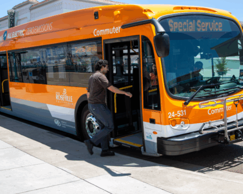 Orange all-electric Roseville Commuter bus with ‘Special Service’ on the display, with a rider boarding.