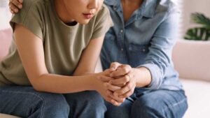 Person receiving emotional support from another individual, with their hands clasped together in a moment of connection, representing therapeutic relationships that benefit sensitive individuals.