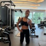 Serena Williams taking a mirror selfie in a gym wearing black workout attire, showing her toned abdomen and physique.