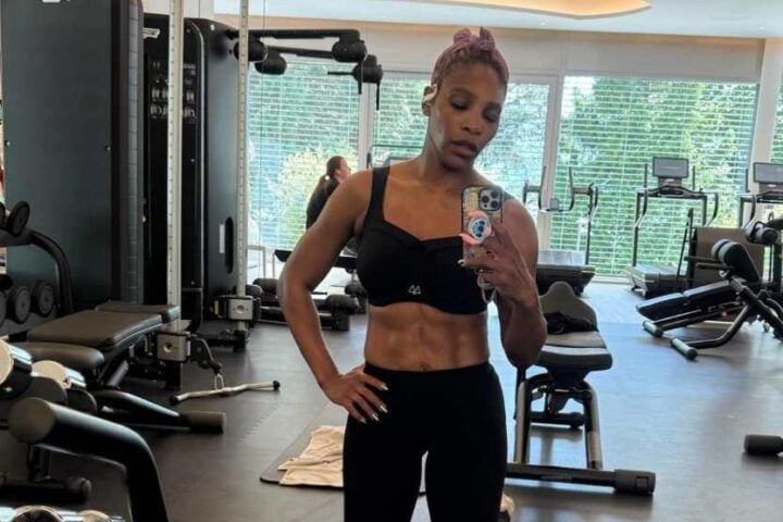 Serena Williams taking a mirror selfie in a gym wearing black workout attire, showing her toned abdomen and physique.