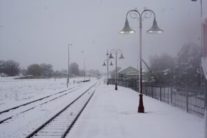 Snow-covered railway tracks and platform at Orange railway station, New South Wales, Australia. Ornamental lamp posts line the tracks, and snow blankets the surrounding area creating white-out conditions.