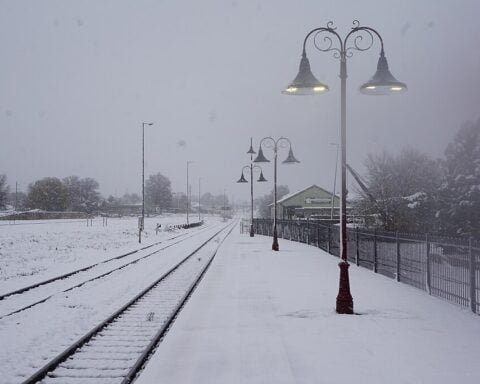 Snow-covered railway tracks and platform at Orange railway station, New South Wales, Australia. Ornamental lamp posts line the tracks, and snow blankets the surrounding area creating white-out conditions.