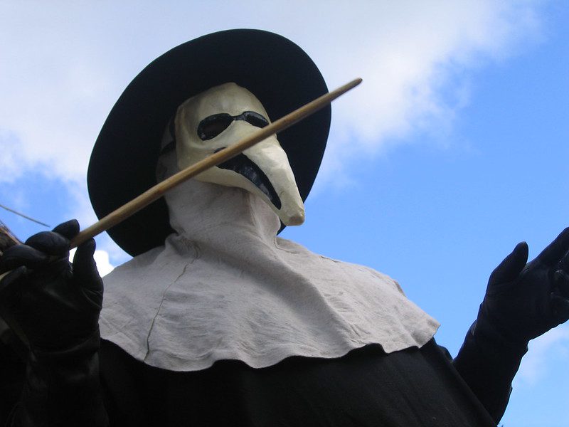 Historical depiction of bubonic plague protection methods including herbal nose filters and touch-avoidance tools