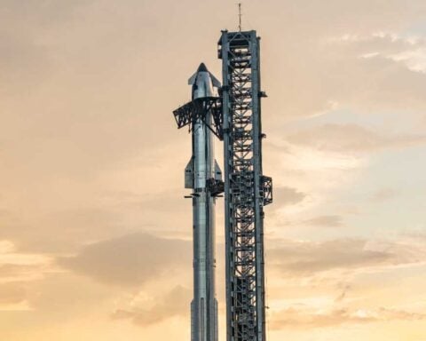 SpaceX Starship rocket mounted on its Super Heavy booster at the launch tower during sunset at Starbase facility in Texas.