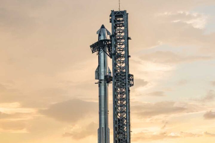 SpaceX Starship rocket mounted on its Super Heavy booster at the launch tower during sunset at Starbase facility in Texas.