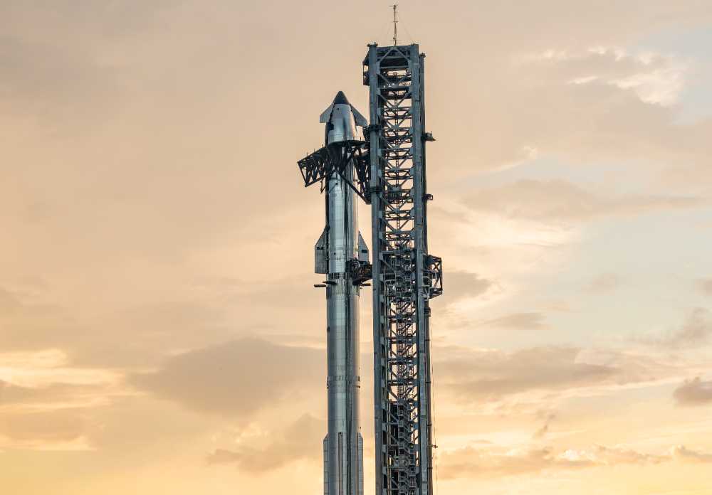 SpaceX Starship rocket mounted on its Super Heavy booster at the launch tower during sunset at Starbase facility in Texas.