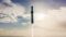 SpaceX Starship rocket ascending through clouds with engine firing during Flight 10 test, silhouetted against a bright blue sky with scattered white clouds.