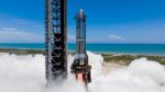 Starship on Pad 1 at Starbase during single‑engine static fire with exhaust plume, ocean and clear sky in background