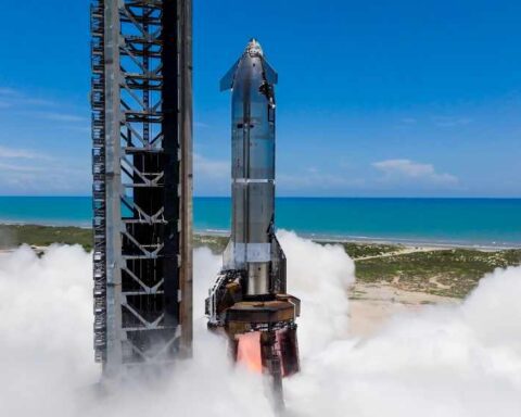 Starship on Pad 1 at Starbase during single‑engine static fire with exhaust plume, ocean and clear sky in background