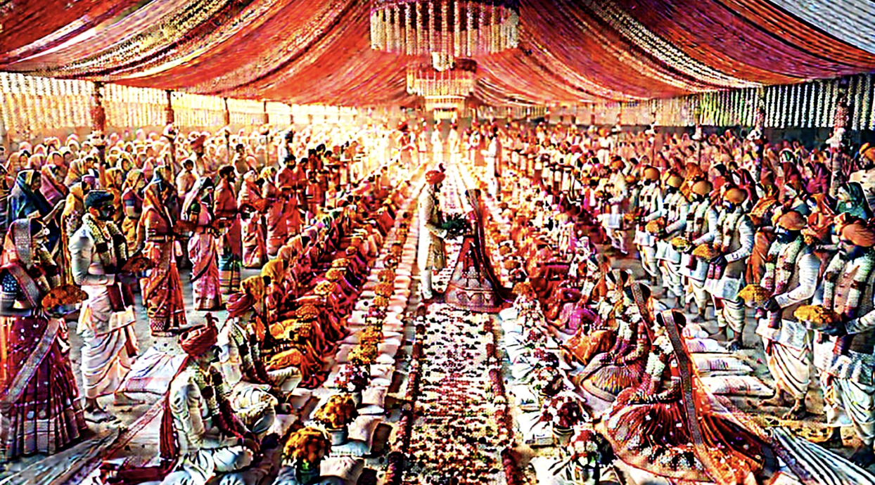 Rows of dozens of Indian brides and grooms in traditional attire seated side by side under a decorated canopy during a large-scale community mass marriage ceremony.