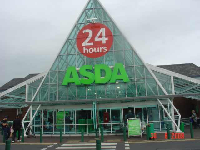Front entrance of Asda Blackburn supermarket with “24 hours” sign above the main glass façade.