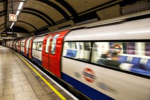 London Underground train arriving at a curved platform with TfL roundel and safety markings visible.