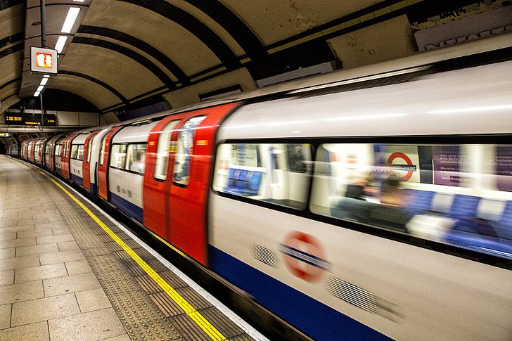 London Underground train arriving at a curved platform with TfL roundel and safety markings visible.